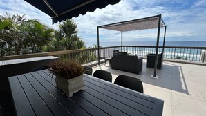 Una terraza con vistas al mar, mobiliario para exteriores y una zona cubierta.