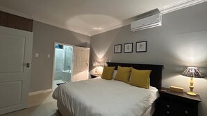 Un dormitorio con una cama, lámparas de noche, una mesita de noche y una puerta que da a un baño.