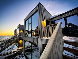 Ein modernes Gebäude mit Glasfassade, einer Holztreppe und Blick auf das Wasser.