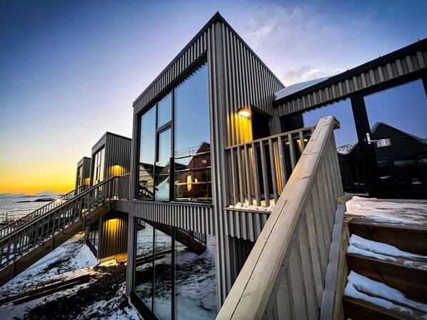 A modern building with a glass facade, a wooden staircase, and a view of the water.