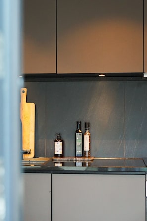 A kitchen with a wooden cutting board, two bottles of hand soap, and a black countertop.