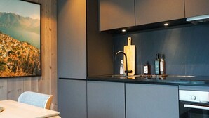 A modern kitchen with a wooden ceiling, grey cabinets, a wooden cutting board, a sink, and a built-in oven.