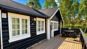 A log cabin with a deck, large windows, and a chimney.