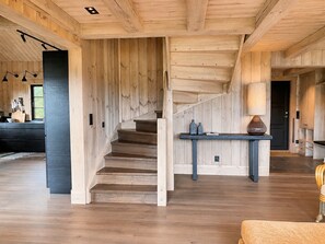 A wooden interior with a staircase, a dining area, and a kitchen.