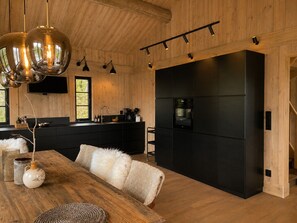 Eine moderne Küche mit einer schwarzen Kochinsel, Holzbalkendecke und Pendelleuchten.