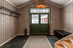 Un intérieur en bois avec une porte verte, un banc noir et un luminaire suspendu.