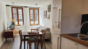 A modern kitchen with wooden cabinets, a dining area with a table and chairs, and a sofa.