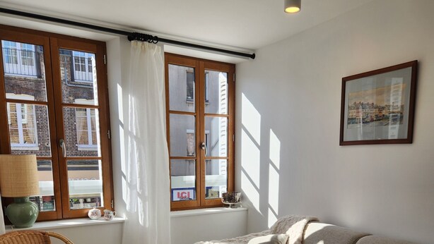 A living room with a sofa, a chair, a table, and a window with curtains.