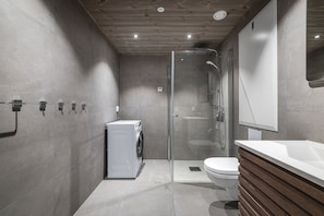 A modern bathroom with a glass shower enclosure, a built-in washing machine, a toilet, and a wooden vanity with a mirror. - Hemsedal ski in/ski out – new apartment with everything you need (Hemsedal)