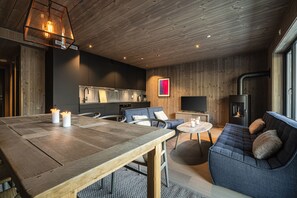 Ein modernes Interieur mit Holzbalkendecke, einem Esstisch mit Kerzen, einer Couch und einem Kamin.