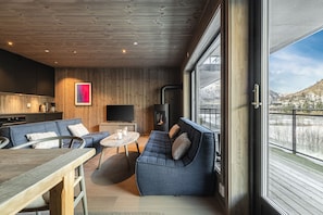 A modern living room with a sofa, a dining table, and a fireplace. - Hemsedal ski in/ski out – new apartment with everything you need (Hemsedal)