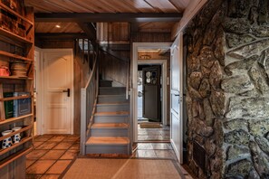A wooden staircase leading to a door, a stone wall, and shelves with kitchen items.