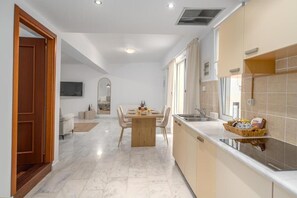 Une cuisine moderne avec un coin repas, une porte en bois et un téléviseur en arrière-plan.