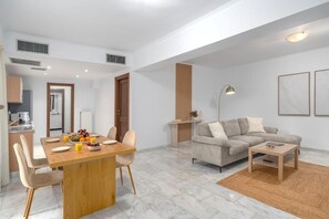 Ein modernes Wohnzimmer mit einer Couch, einem Couchtisch und einem Essbereich mit Stühlen und einem Tisch für zwei Personen.