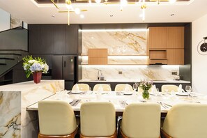 Uma cozinha moderna com bancadas de mármore, armários de madeira e uma área de jantar preparada para seis pessoas.