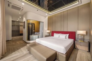 A modern hotel room with a large bed, a red headboard, a bedside table with a lamp, and a walk-in closet. - Vidanang Luxury Villa - 07 Bedrooms - Pool - Sauna - Karaoke - BBQ - Lift (Đà Nẵng)