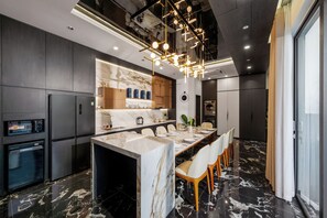A modern kitchen with a marble island, built-in appliances, and a dining area with a long table.