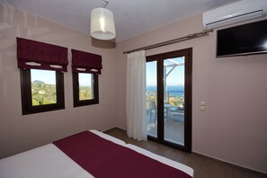 Quarto com cama, televisão, janela com cortinas e vista para o exterior.