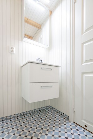 A bathroom with a white vanity, a mirror, and a checkered floor.