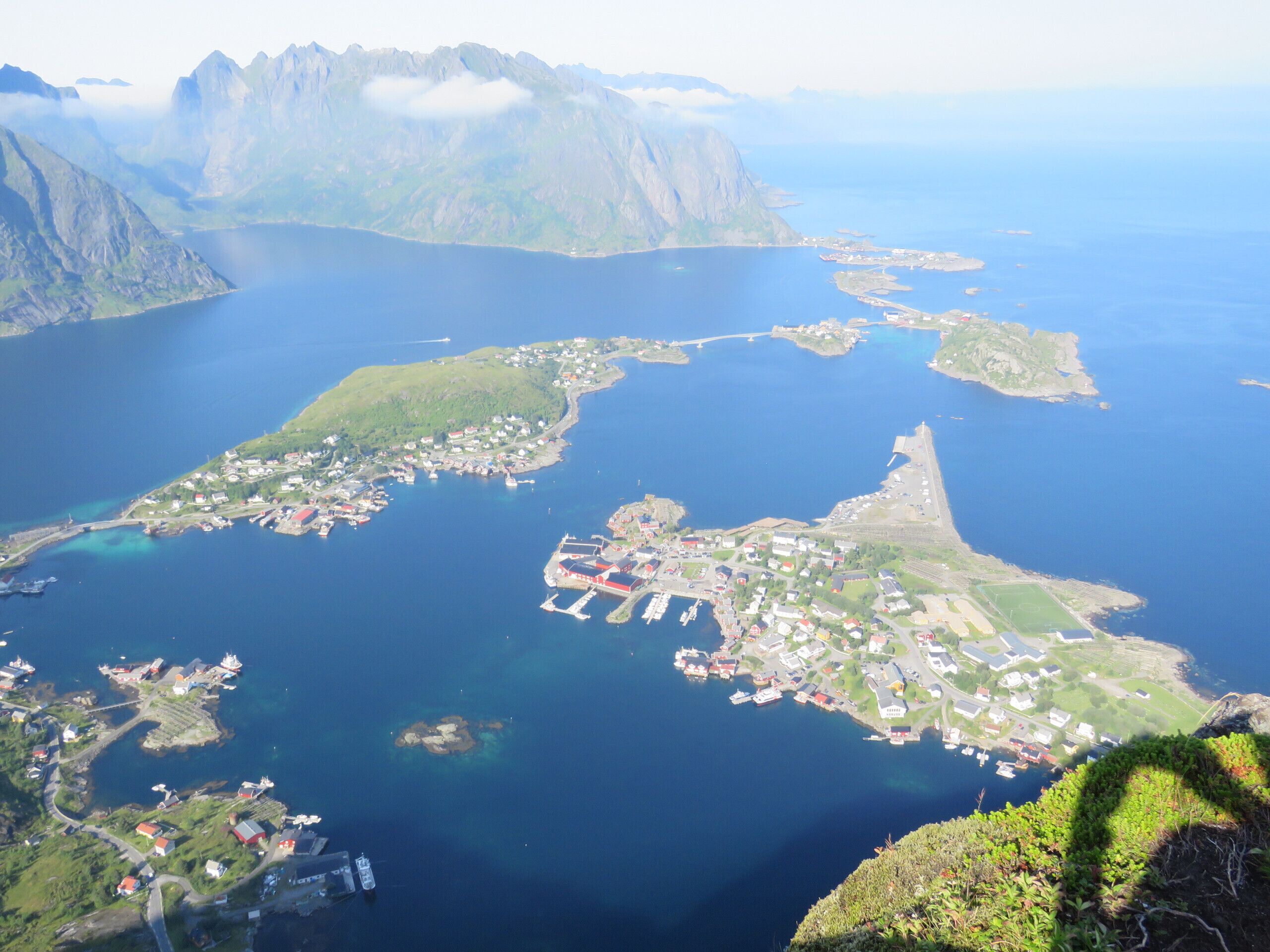 Vue aérienne d’une ville côtière avec un port, des bâtiments et les montagnes environnantes.