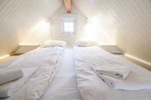 Quarto com duas camas, uma janela e teto inclinado.