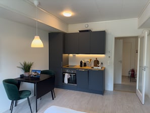 A modern kitchen with dark cabinets, a wooden countertop, and a built-in oven. - Studio Vestermyrveien, Svolvær (Vågan)