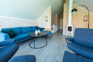 A modern living room with a blue sofa, a round coffee table, and a blue armchair. - Lofoten Waterfront luxury lodge (Vestvågøy)