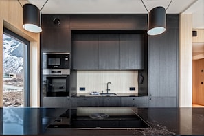 A modern kitchen with a built-in microwave, oven, and a large sink.