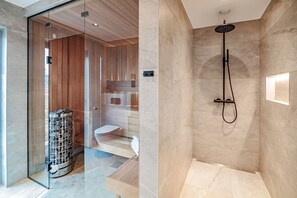 Ein modernes Badezimmer mit Duschkabine aus Glas, einem Holzwaschtisch und einem Boden aus Marmorplatten.