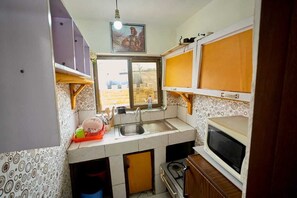 Pieni, käytännöllinen keittiö, jossa on pesuallas, mikroaaltouuni ja liesi.