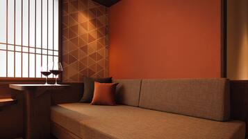 A modern interior with a sofa, a table, and a window with vertical blinds.