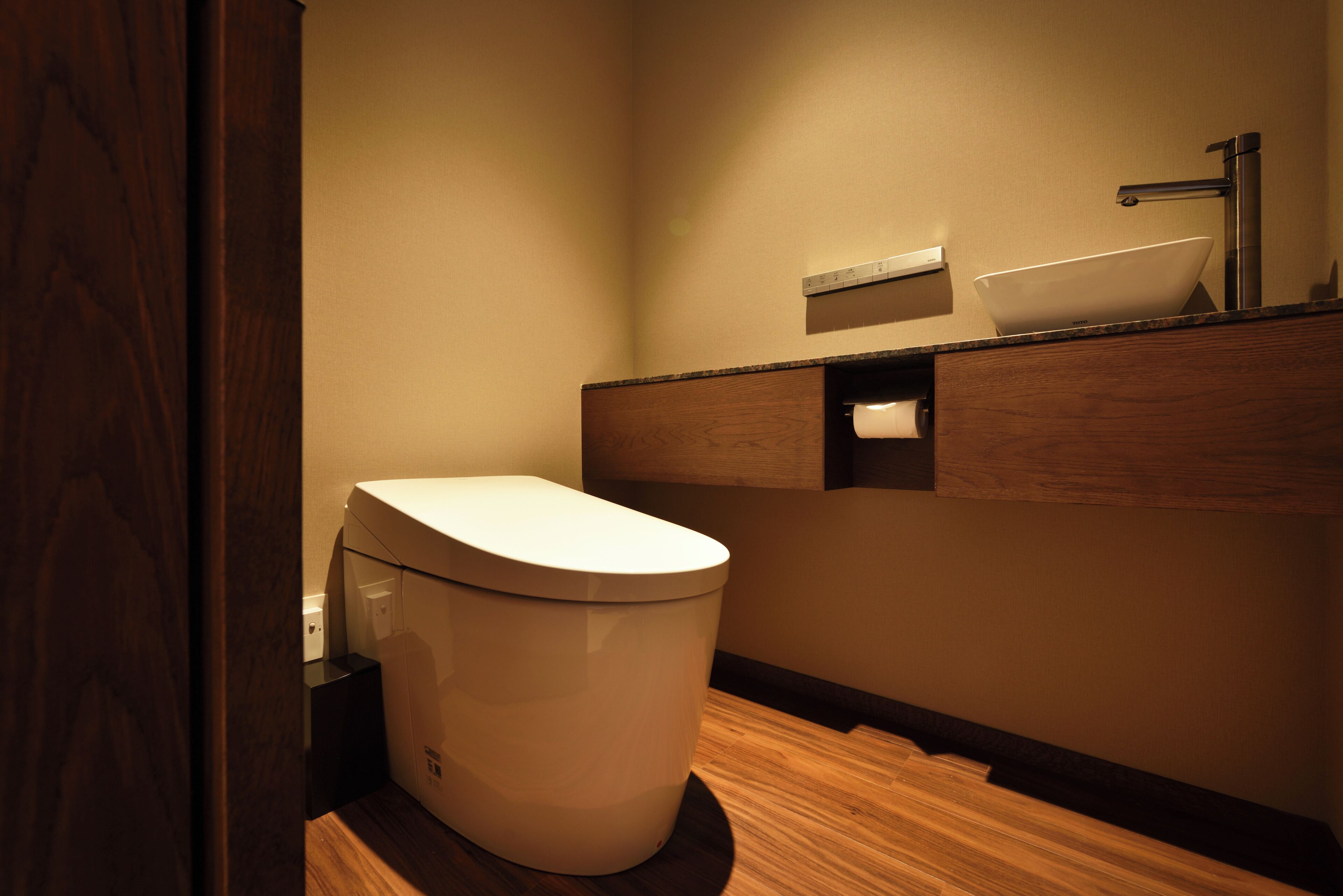 A modern bathroom with a toilet, a sink, and a wooden vanity.