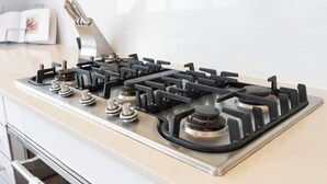 A kitchen with a gas stove, a range hood, and a stainless steel countertop.
