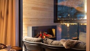 A modern living room with a fireplace, a sofa with a fur throw, and a dining area with a table and chairs.
