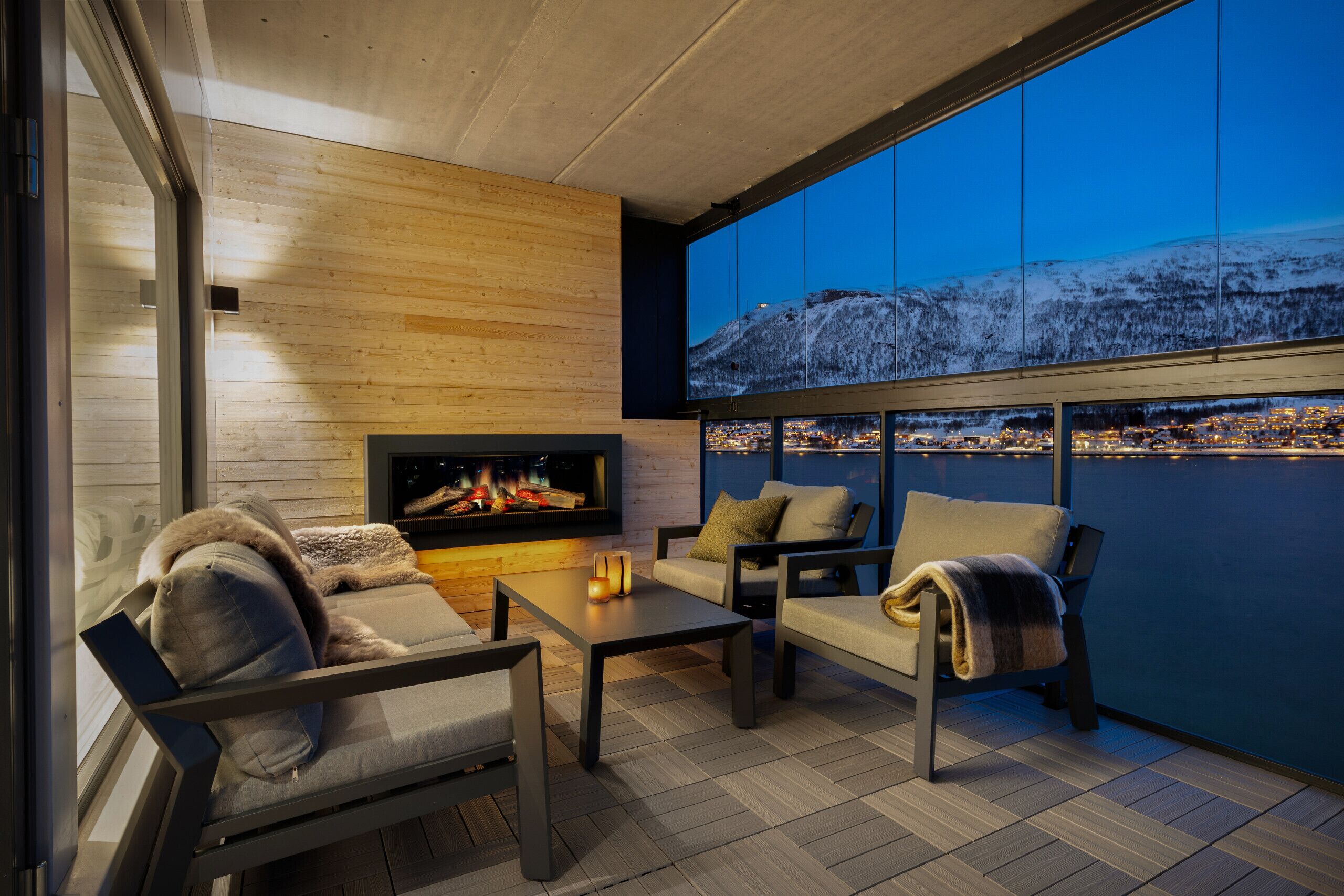 Un espace extérieur moderne, aménagé avec un foyer, des sièges confortables et une grande fenêtre offrant une vue sur la ville.