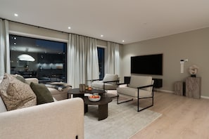 A modern living room with a sofa, armchairs, a coffee table, and a flat-screen TV. - Premium Waterfront Apartment with Stunning View (Tromsø)