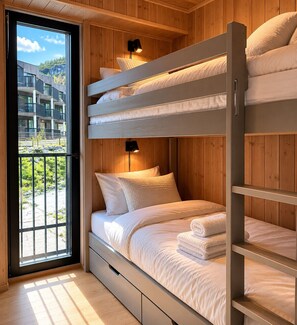 Een slaapkamer met stapelbedden, houten wanden, een raam met uitzicht op gebouwen en groen, en twee bedlampen.
