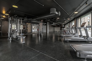 A gym with treadmills, weight machines, and a mirrored wall.