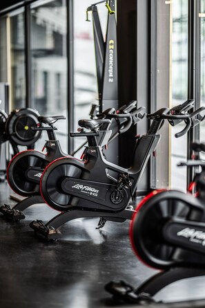 Una bicicleta estàtica a la sala de gimnàstica, amb una barra de peses al fons.