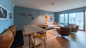 Un salon moderne avec un canapé, une table à manger, une table basse et un balcon offrant une vue agréable.
