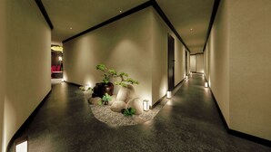 A hallway with a curved ceiling, recessed lighting, and a small garden area with plants and rocks. - Amiana Hotel Hanoi (Hanoi)
