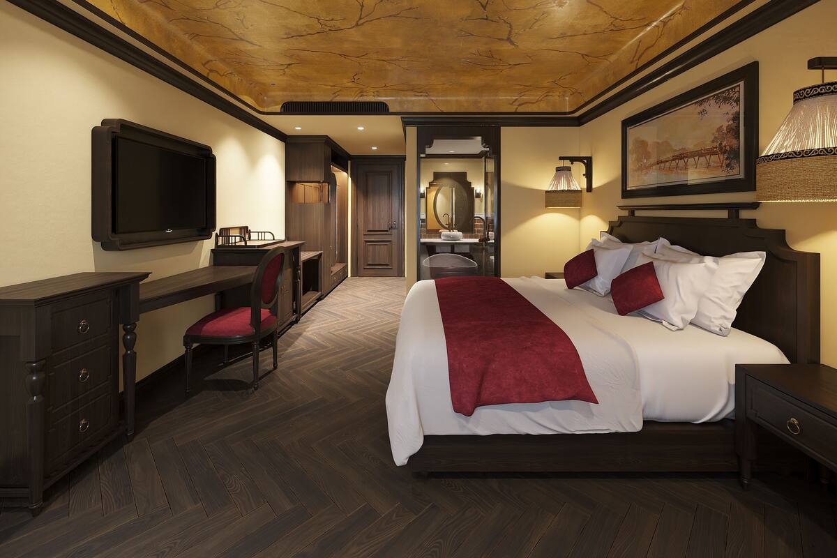 Una habitación de hotel con cama, escritorio, silla, televisor y espejo.
