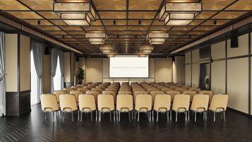 A conference room with rows of chairs, a projector screen, and a wooden ceiling.