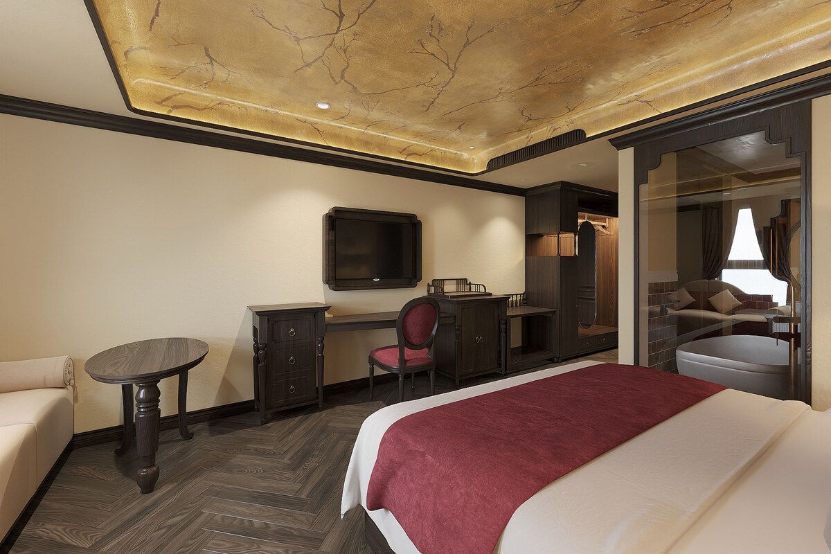 Ein Hotelzimmer mit Bett, Schreibtisch, Stuhl, Fernseher und Kleiderschrank.