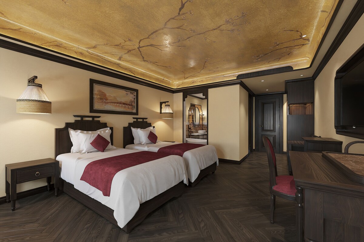 Ein Hotelzimmer mit einem großen Bett, einem Schreibtisch, einem Sessel und einem Fernseher.