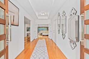 A hallway with wooden floors, white walls, and a patterned rug. - Modern and luxury private Home (Piara Waters)