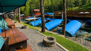 Un camping con varias tiendas de campaña, mesas de madera y un brasero.