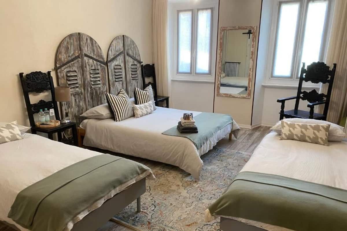 Una habitación con dos camas, un espejo grande y una ventana con cortinas.