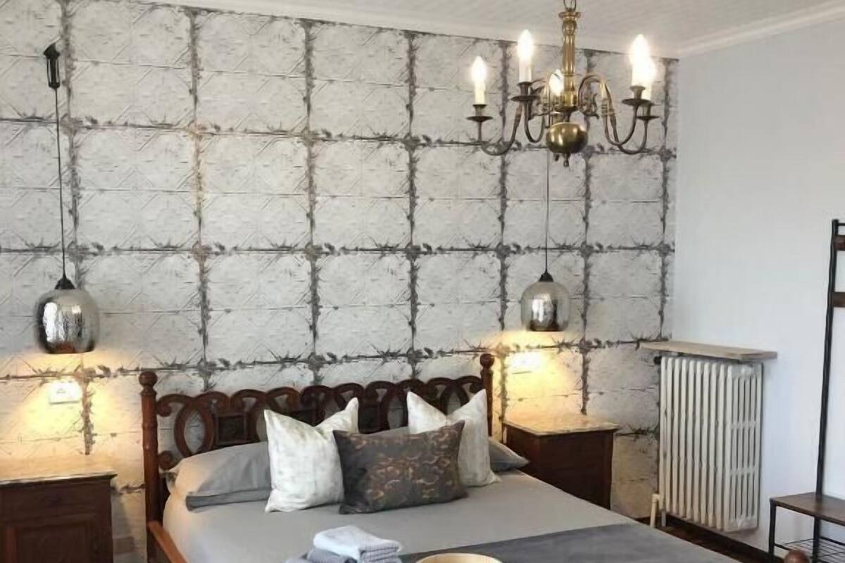 Un dormitorio con una cama de madera, un papel tapiz estampado y una araña.