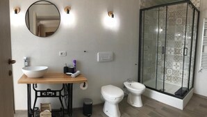 Un baño con lavamanos, espejo, inodoro, bidé y cabina de ducha.